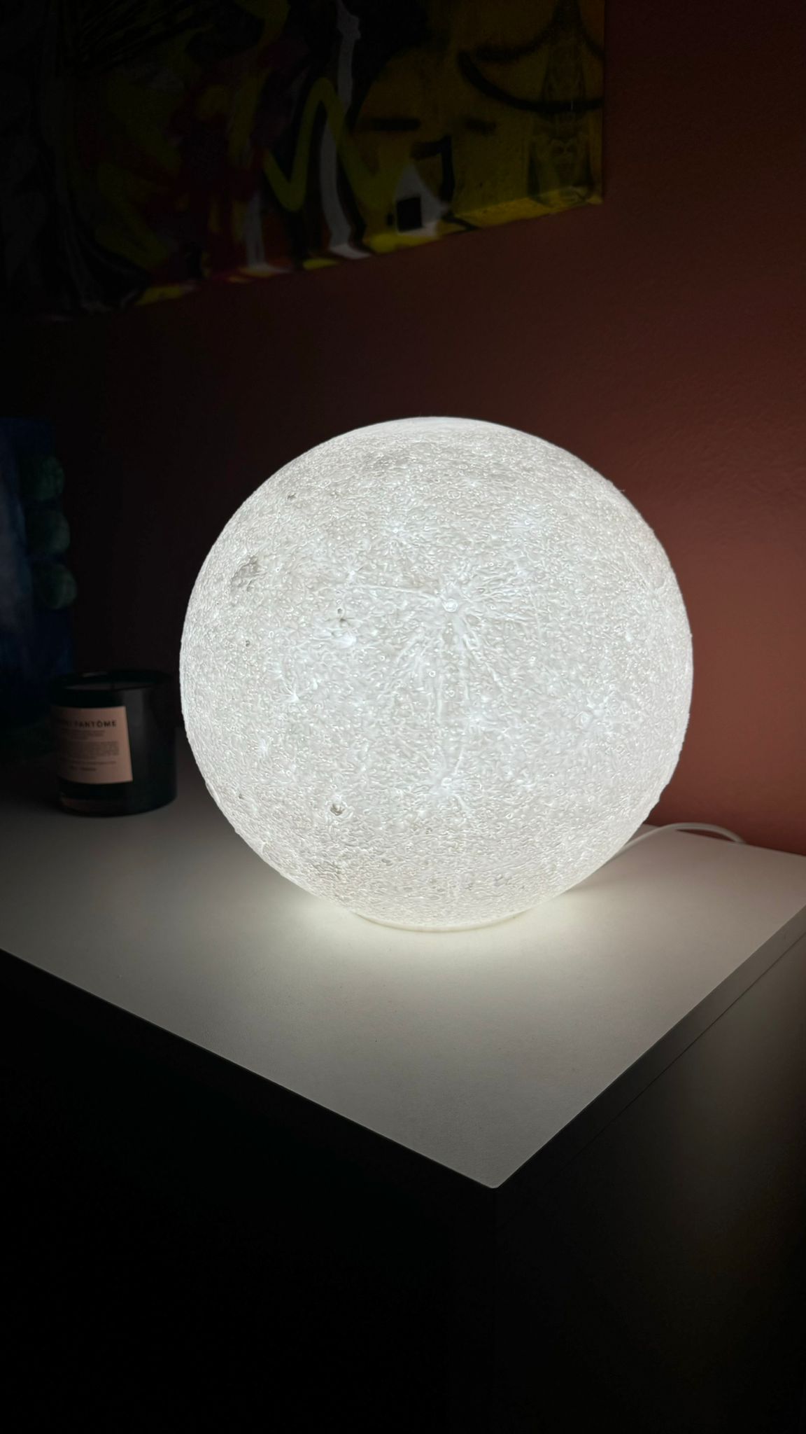 3D printed moon night light on a stand, showing starry night effect.