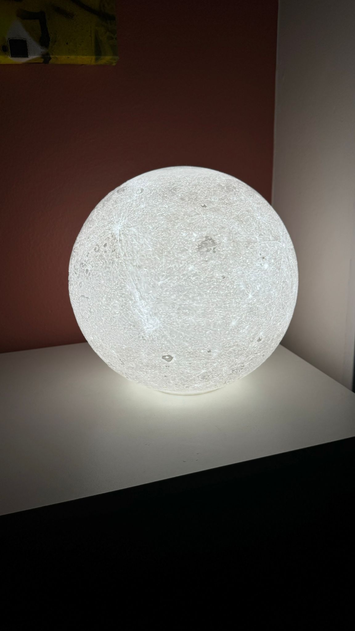 3D printed moon night light in a dark room, showing realistic moon effect.